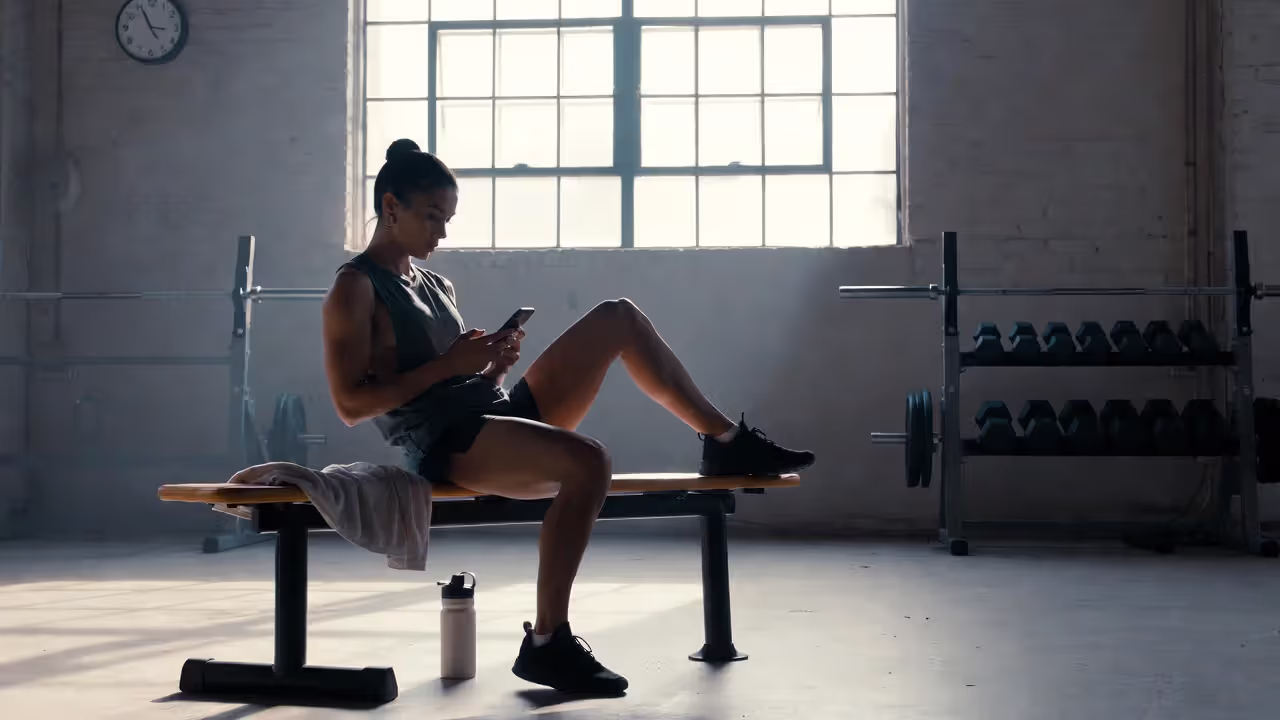 Athlete sitting and checking phone instead of cooling down after workout
