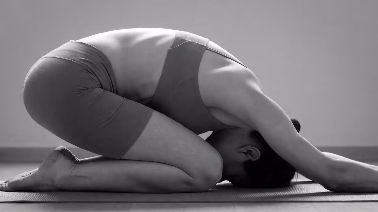 Person performing Child’s Pose with torso folded forward and arms extended on a yoga mat.