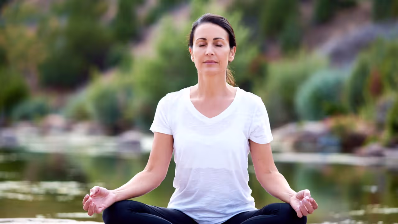 Person demonstrating alternate nostril breathing hand position with thumb closing one nostril.