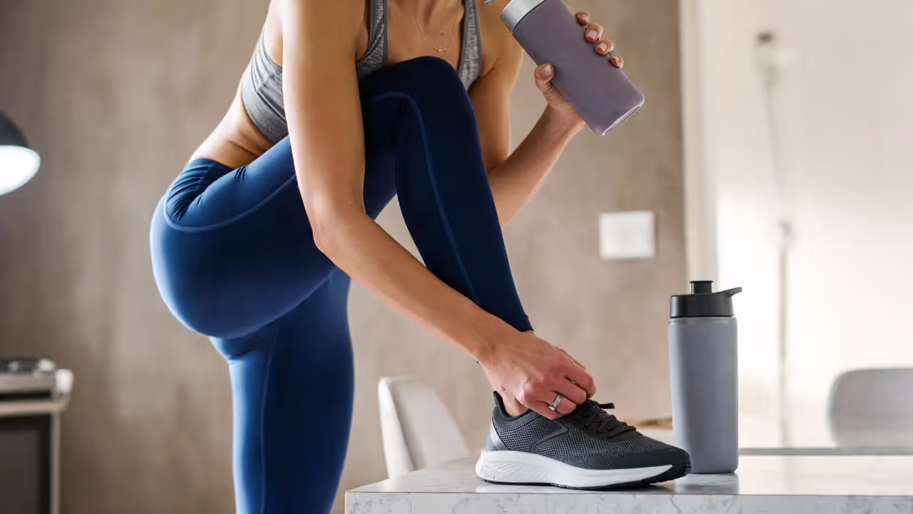 Person preparing for a morning workout at home, tying shoes in natural light