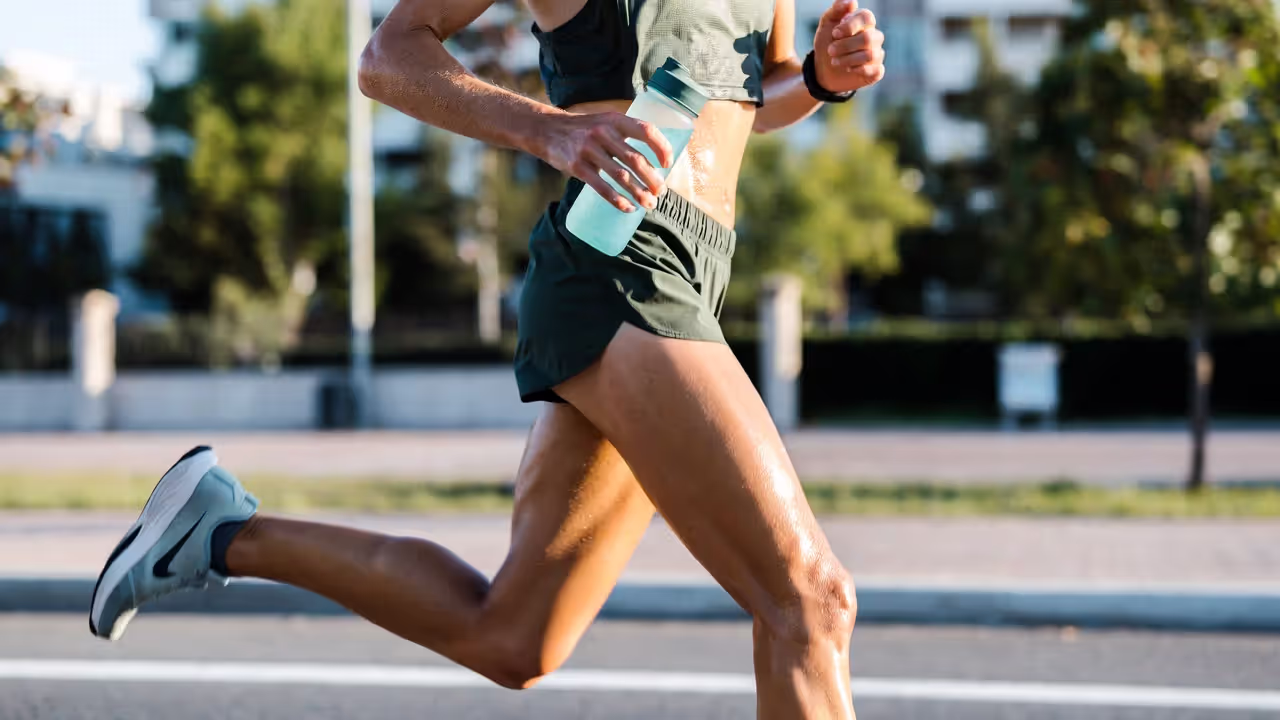 Runner sweating during intense workout holding a water bottle