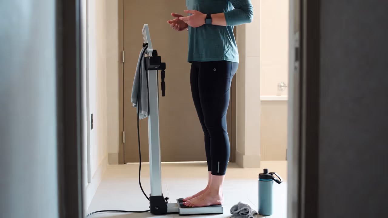 Athlete standing on scale with water bottle nearby to measure sweat loss